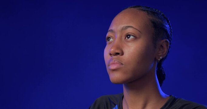 African American woman holding upward gaze, turning head to camera in studio wearing blue shirt