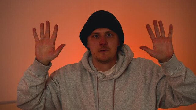 Arrest of masked criminal raising his hands with police lights in the background.
A dangerous criminal raises his hands and surrenders to the police.