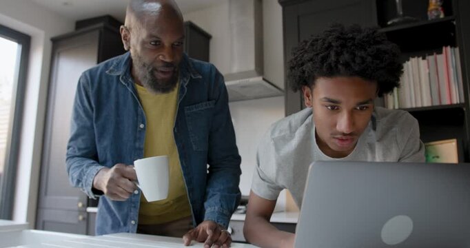Father Supporting Child Education in Kitchen with Laptop computer Technology