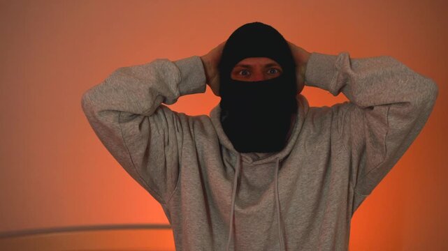 A masked suspect surrenders with his hands raised during a police arrest, with officers flashing their lights in the background.
Dangerous asylum seeker caught red-handed