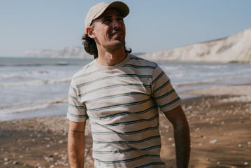 Man stands barefoot on pebbled beach © Reuben