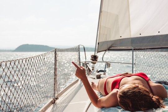Woman relaxing on sailboat pointing at distant view