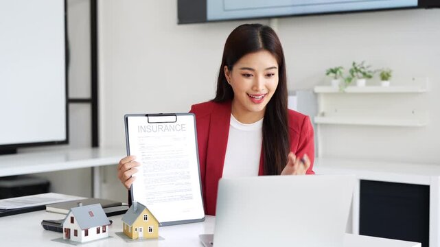 Online operation of buying and selling real estate. businesswoman realtor sit in office talks on a video call with clients, shows contract insurance to camera and offers product contract options.