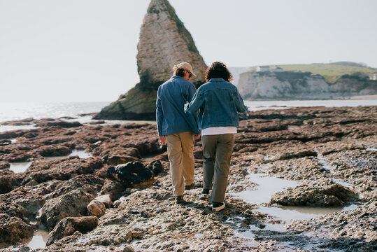 Two people stroll along wet, rocky tide pools