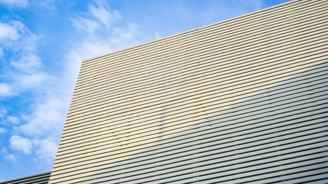 Modern building facade with horizontal lines against a blue sky.