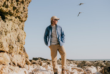 Man stands on rocky shore, gazing toward sea © Reuben
