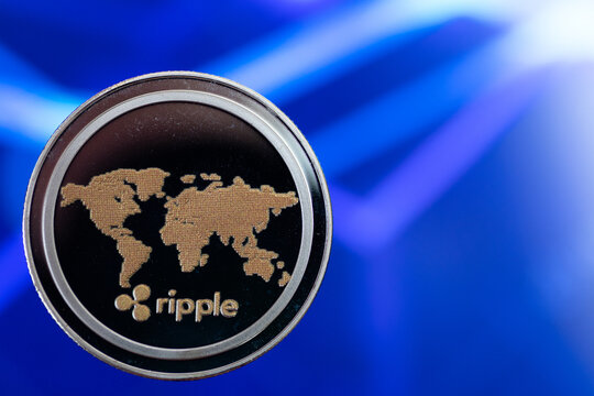 Ripple Cryptocurrency Coin on Blurred Financial Chart Background in Blue Tones