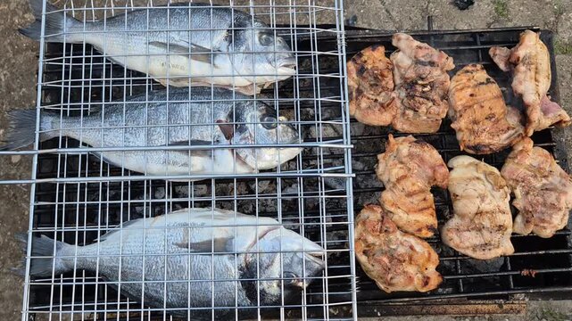 Three whole sea bream and chicken thighs sizzle over hot charcoal on an outdoor grill, capturing the essence of a perfect summer barbecue.