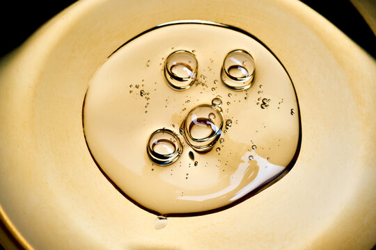 Gold liquid oil dropping with bubbles surface
