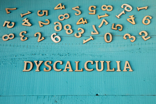 Dyscalculia word and chaotically scattered digits on a blue-painted wooden background - learning disabilities concept.