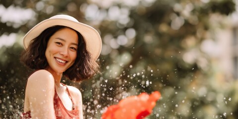 Naklejka premium Young woman laughing with water splash in outdoor garden