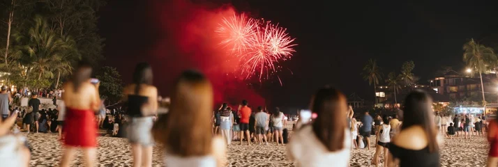 Group watching fireworks from sandy beach with resort backdrop © Andrii Zastrozhnov