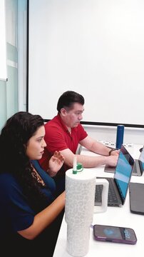 Woman and man professionals analysing data on laptops during meeting