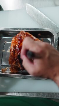 Chef seasoning pork with sweet marinade before roasting in a professional kitchen