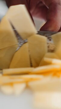 Chef slicing fresh potatoes with a kitchen knife on a white cutting board
