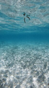 Blue ocean underwater and sandy sea bottom with waves on sunny day