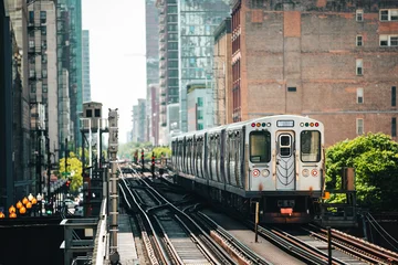 Train of public transportation arriving on elevated railway above busy street in downtown Chicago. Urban transport, city life, infrastructure, and daily commute concept. © Chalabala