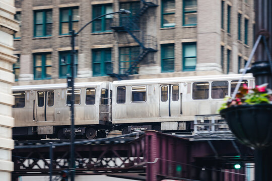 Train of public transportation on the move on elevated railway above street in downtown Chicago. Urban transport, city life, infrastructure, and daily commute concept.