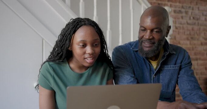 Father and Daughter Engaged in Learning on Laptop at Kitchen Table