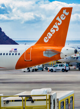 Tenerife South Airport, Spain, April 5, 2026 - Tail of an easyJet aircraft on the apron at Tenerife South Airport with service vehicles, sea and mountains in the background.