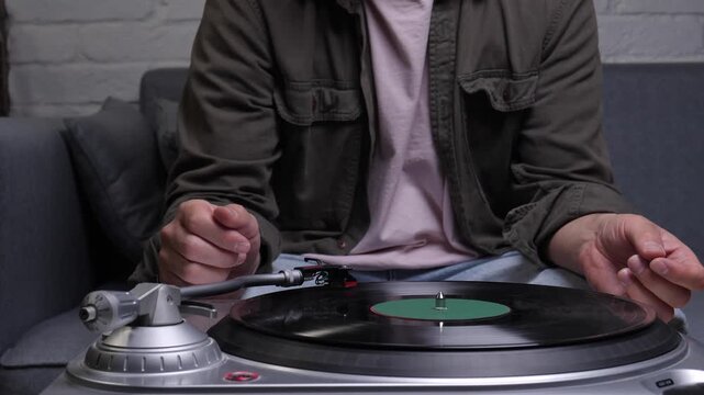 Enjoying retro style music, a person is placing the stylus on a spinning vinyl record, highlighting the timeless hobby of analogue audio entertainment and relaxation