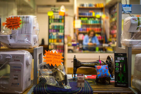 Feria, Seville, Andalusia, Spain &ndash; Feb 13, 2020: A bustling haberdashery store window showcases a diverse array of sewing machines, including a classic Singer model and modern overlockers with discoun