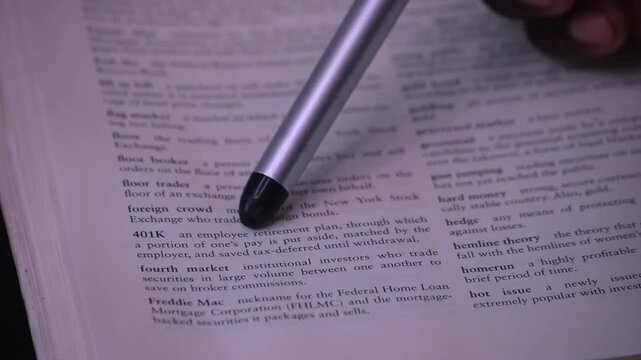 Person reviewing 401(k) plans and financial options in a book, exploring retirement savings, investing, and personal finance planning.