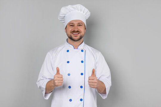 Professional chef showing thumbs ups on grey background