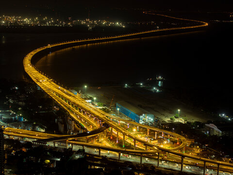 India's Longest Sea Bridge: Trans-Harbour Sea Link. Atal Setu sea bridge in Mumbai, Maharashtra, India. A city at night with bright skyscrapers and a dense network of glowing buildings.