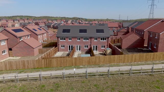Slow zoom inof a row of new build terraced houses on construction site with in-built solar panels for cheap and sustainable energy bills