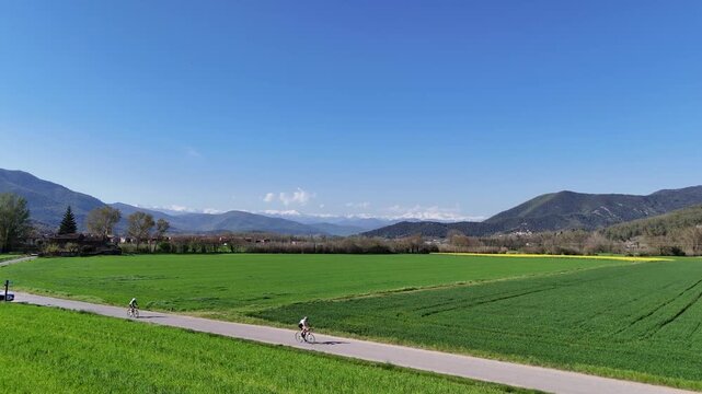 Cyclists training in Vall d'en Bas green countryside