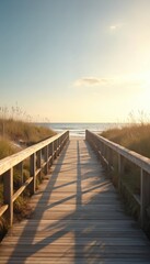 Fototapeta premium Wooden walkway leads over sand dunes to ocean beach at sunset. Gentle waves meet sandy shore under warm sky. Peaceful seaside path invites nature stroll.