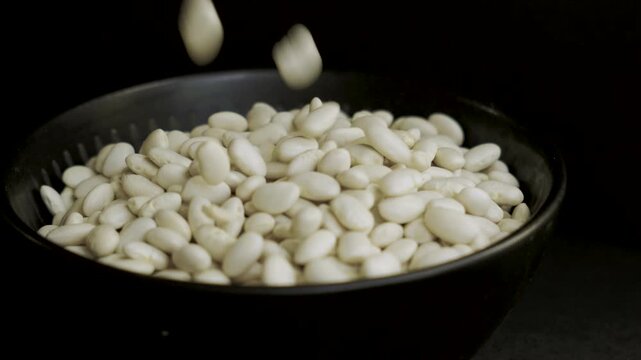 White lima beans filling black bowl on black background 4k 10bit 120fps