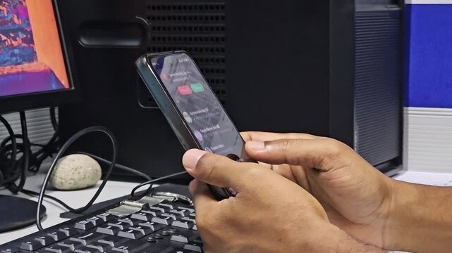 Smooth Mobile Screen Scrolling Demo &ndash; Touch Display Performance Test. Hand holding a smartphone and quickly scrolling a social media feed with a desk in the background.