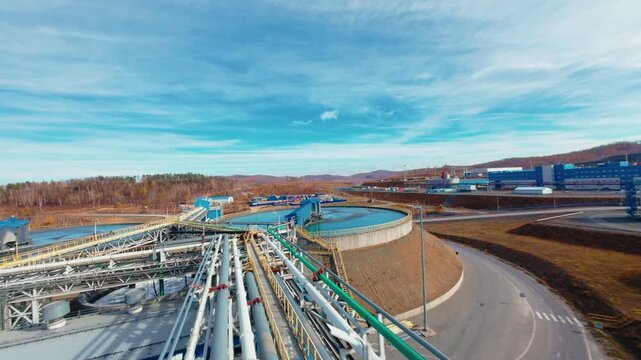 Aerial tracking shot of industrial plant tanks and pipelines processing water treatment at mining on copper factory.