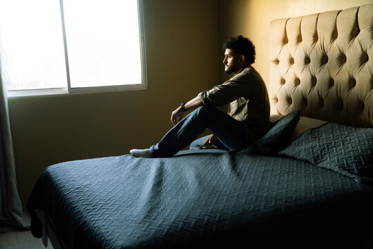 Man reflecting in bedroom, feeling pain and anxiety