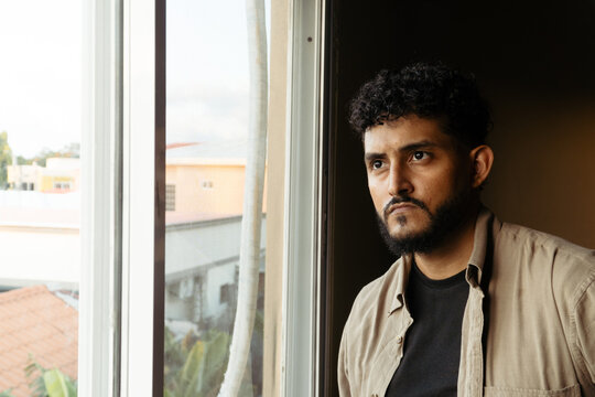 Man thinking by window experiencing solitude and mental health struggles
