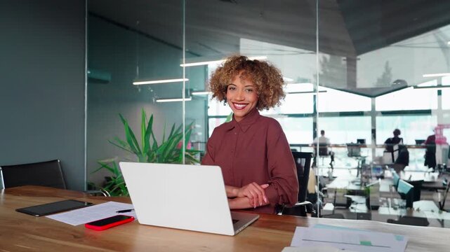 Beautiful African American mature business woman smiling at camera at office workplace. Young latin confident good looking middle-aged leader female CEO businesswoman at work in office workspace