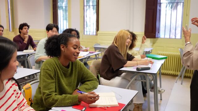 University classroom with a multicultural group of students listening to a professor and taking notes. Young people learning in a lecture