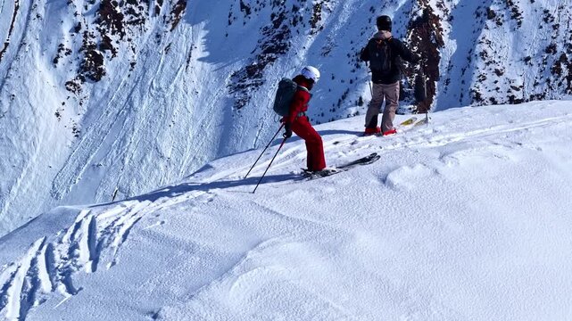 Two skiers traversing steep snow covered mountain slope in Nauders Austria, trekking to top of peak and taking in grand view, aerial parallax
