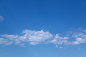 Fototapeta premium A wide expanse of bright blue sky dotted with fluffy white clouds, conveying calm, openness and a sunny summer mood ideal for backgrounds, weather concepts, nature scenes and minimalist design.