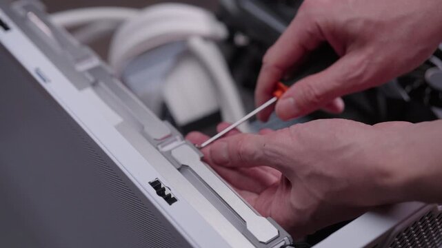 Computer technician assembling personal computer case by tightening fan screw, concept of professional electronic hardware maintenance, repair, upgrade service, close-up. Shooting in slow motion.