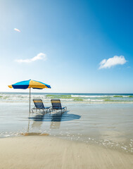 Beach chairs and a parasol on the sand in a beach on a sunny day © Gabriele Maltinti