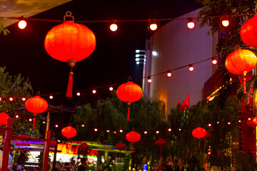 Red lanterns glowing at night with string lights creating a festive street atmosphere © BloodysAlice