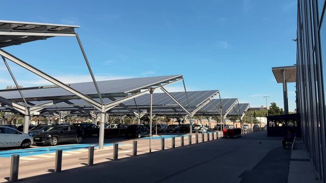 Solar panel canopies covering cars in outdoor parking lot under clear sky