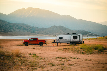 Pickup truck with travel trailer camping near lake in mountains at sunset, road trip lifestyle © Victoria Nefedova