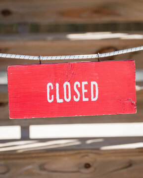 Red closed sign hanging on wooden background