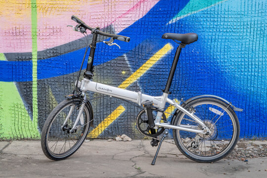 Fort Collins, CO, USA - May 7, 2023: A popular, lightweight, folding bike, Dahon Mariner D8 in an alley against colorful wall mural.