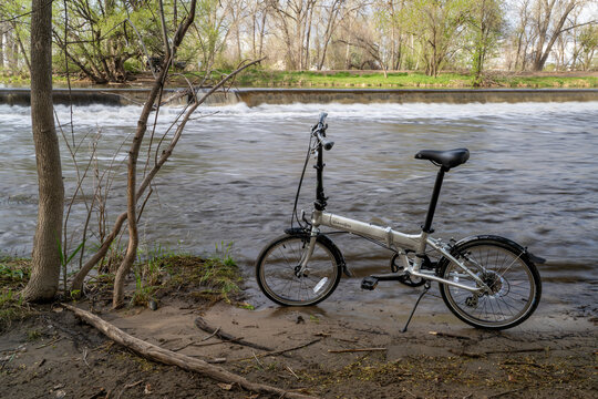 Fort Collins, CO, USA - May 7, 2023: A popular, lightweight, folding bike, Dahon Mariner D8, at whitewater park on the Poudre River in downtown of Fort Collins, Colorado, spring scenery