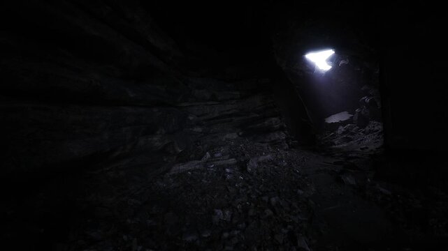 Bright shaft light in dark cavern revealing jagged rocks and damp floor, cinematic moody atmosphere, immersive subterranean texture, high contrast detail